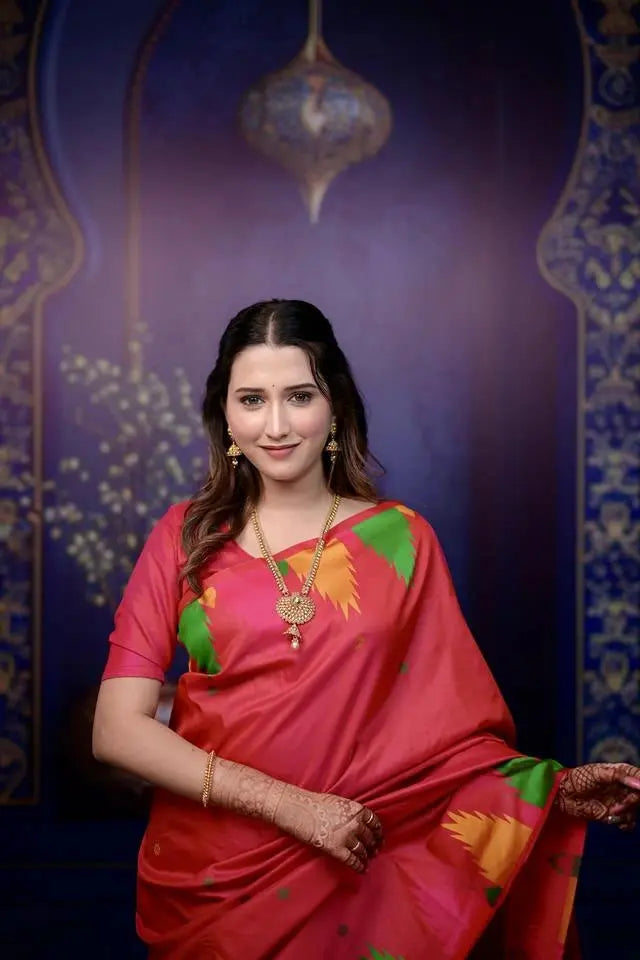 Woman in a red saree with floral patterns against a decorative purple background